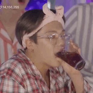 a man drinking from a wine glass while wearing a bunny ears headband on top of his head