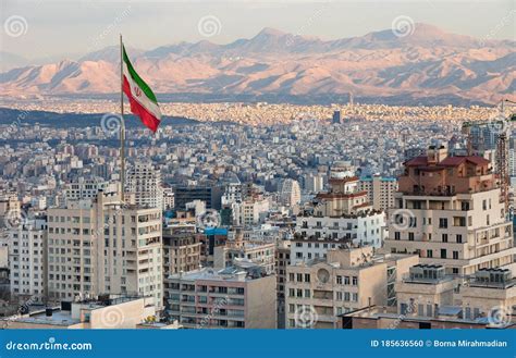 Aerial View of Tehran Skyline at Sunset with Large Iran Flag Waving in ...