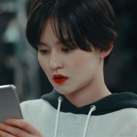 a woman with black hair and red lipstick using a tablet