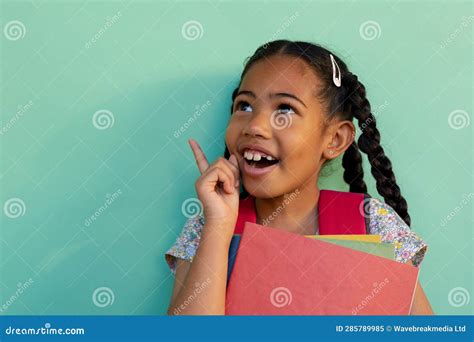 Happy Biracial Schoolgirl with Books Wearing School Bag Over Blue Background at Elementary ...
