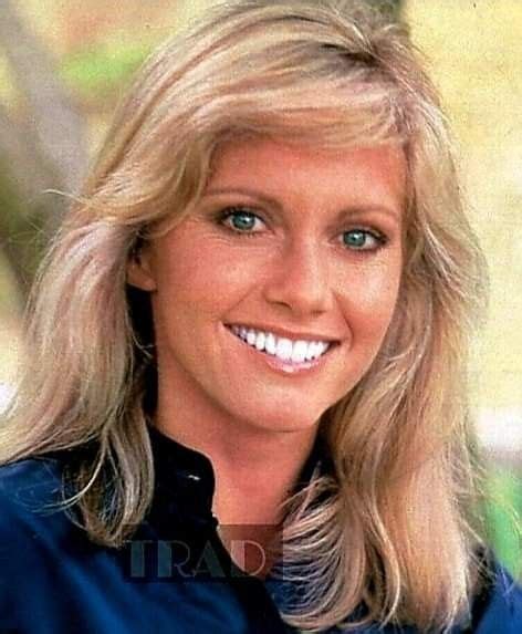 a woman with long blonde hair and blue shirt smiling at the camera in ...