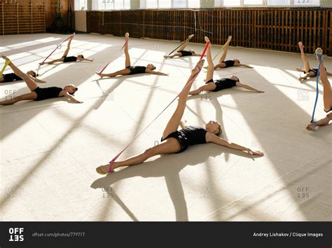 Group of young gymnasts are doing stretching exercises with colorful resistance bands while ...