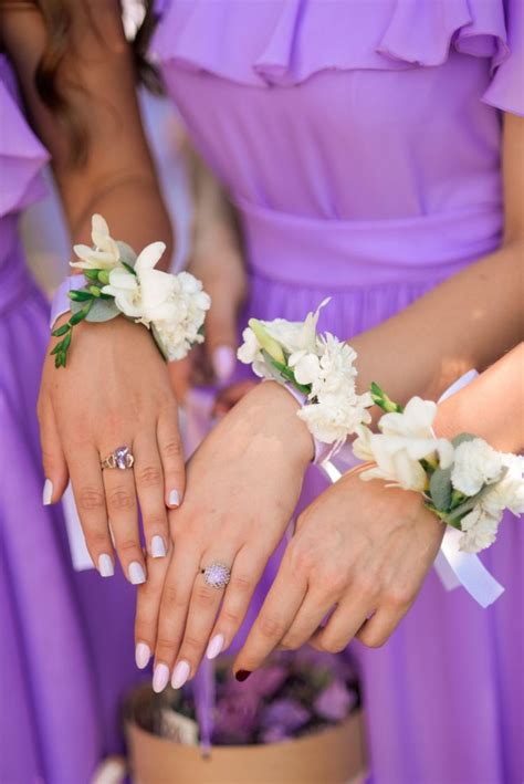 two bridesmaids in purple dresses hold their wedding rings and bouquets over the cake