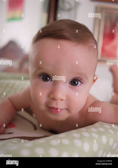 Closeup photograph of a baby smiling at the camera while laying on her stomach on a changing ...