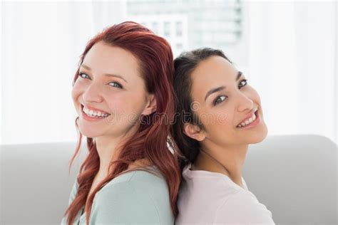 Beautiful Young Female Friends Sitting Back To Back at Home Stock Image - Image of female ...