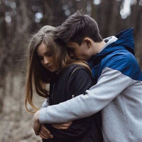 a man and woman hugging in the woods