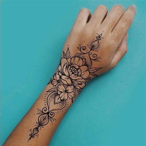 a woman's hand with a flower tattoo on the left wrist and an intricate design on