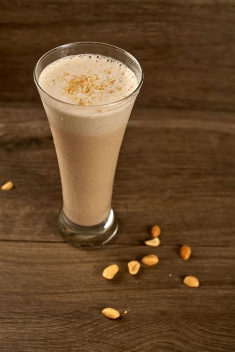 a glass filled with milk and nuts on top of a wooden table