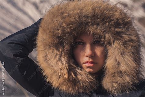 Beautiful girl in a hood with fur of a winter jacket. The girl's face is hidden in a hood with ...