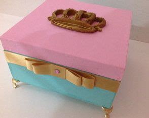 a pink and blue box sitting on top of a white table next to a gold crown