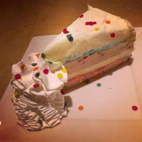 a piece of cake with white frosting and colorful sprinkles on it