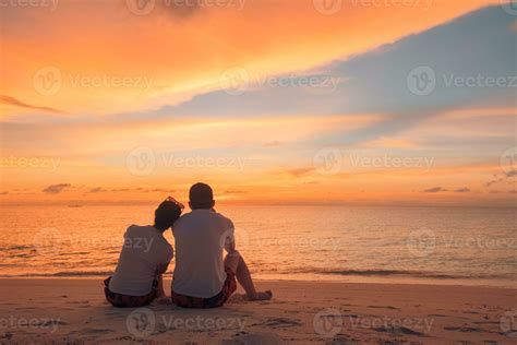 Couple in love watching sunset together on beach travel summer holidays. People silhouette from ...