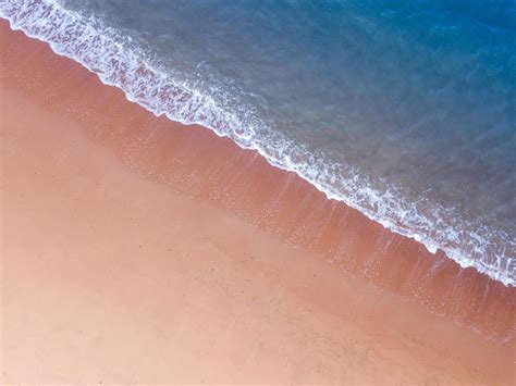 Aerial view of pink sand beach with deep blue sea color and white ...