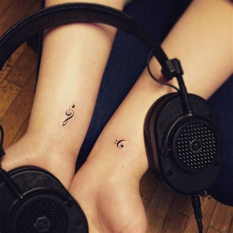 Bass and treble clef tattoos on both wrists.