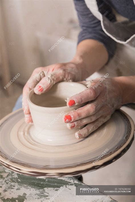 Close up of a woman's hand shaping pottery clay on a pottery wheel in a ceramic workshop ...