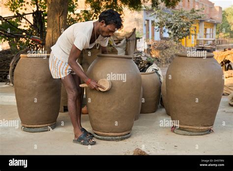 Indian man forming huge clay pots with a wooden tool, Khajuraho, Madhya ...