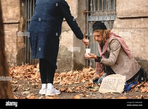 Woman giving money to poor homeless man outdoors Stock Photo - Alamy