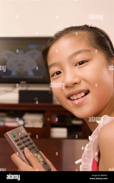 Portrait of a girl holding a remote control and smiling Stock Photo - Alamy