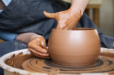 Midsection of woman molding clay in pottery wheel stock photo