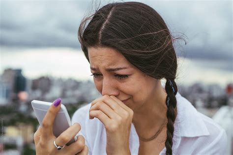 "Woman Looking At Her Phone And Crying" by Stocksy Contributor "Jovo Jovanovic" - Stocksy