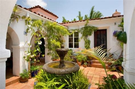 Small infomal Spanish style courtyard entrance to a house with white walls and red tile roof ...