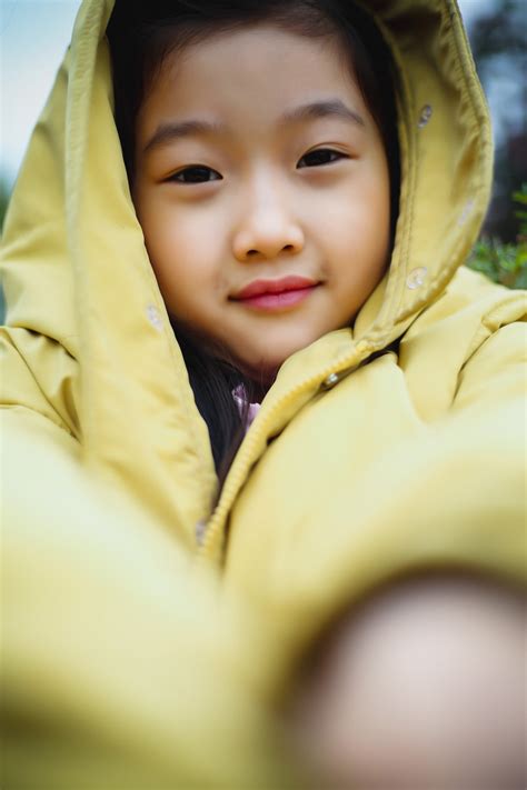 A little girl wearing a yellow jacket and smiling photo – Free Clothing Image on Unsplash