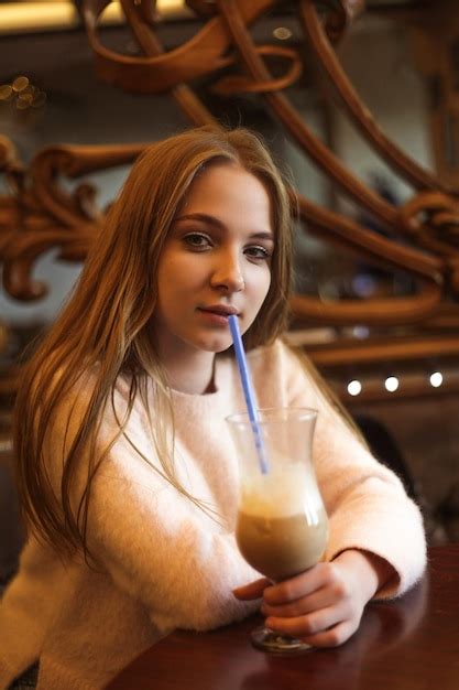 Premium Photo | Beautiful young woman in a cafe with a glass of coffee with milk