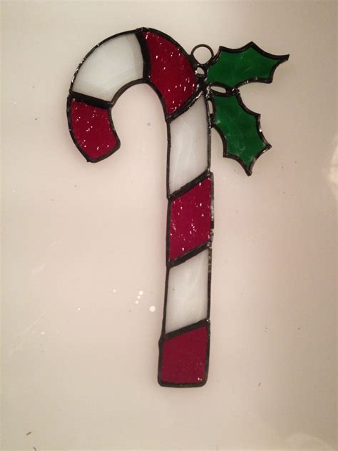 a stained glass candy cane decorated with holly