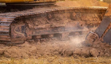 Backhoe working by digging soil at construction site. Bucket teeth of backhoe digging soil ...