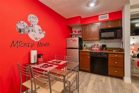 a kitchen with red walls and wooden cabinets, including a small dining table set for four