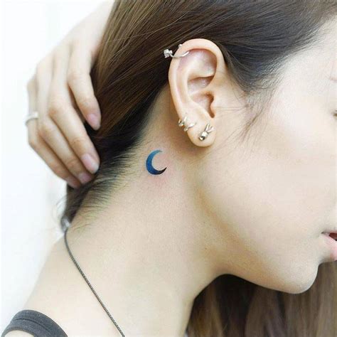 Blue crescent moon tattoo behind the right ear.