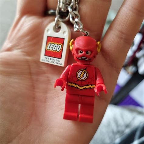 a hand holding a lego minifigure keychain with a flash logo on it