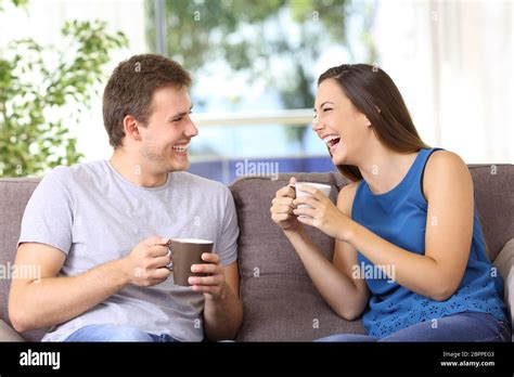 Two people talking and laughing loud sitting on a sofa at home Stock Photo - Alamy