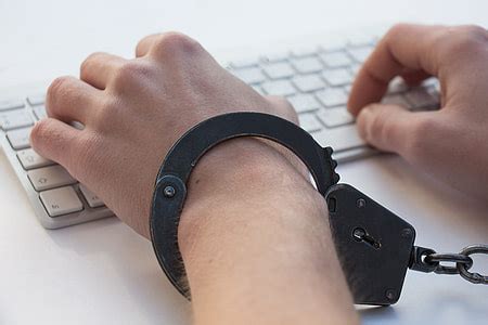 Royalty-Free photo: Person with handcuffs typing on the white keyboard ...