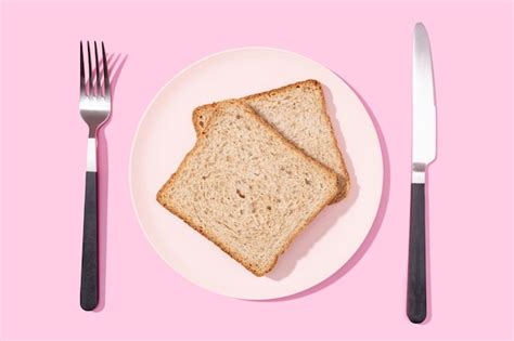 Premium Photo | Flat lay of whole wheat sandwich bread on plate fork and knife on pink background
