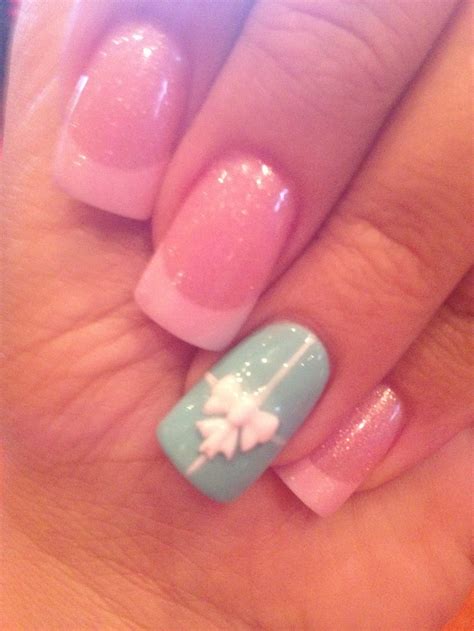 a woman's hand with blue and pink nail polishes on her nails, which are decorated with white flowers