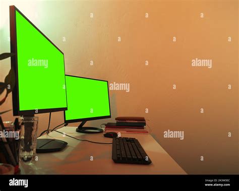 White office desk with two monitors on it green screens turned on for copy space Stock Photo - Alamy