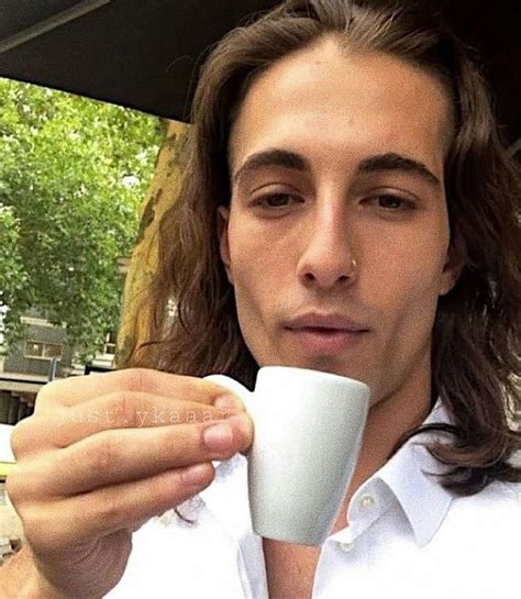 a man with long hair holding a coffee cup