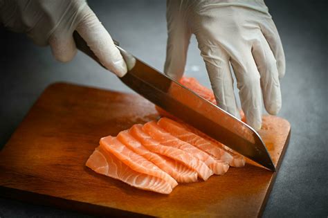 salmon fillet on wooden cutting board, fresh raw salmon fish fillet with kitchen knife for ...