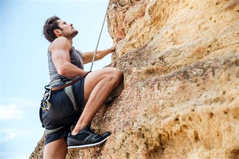 Young man climbing a steep wall in mountain