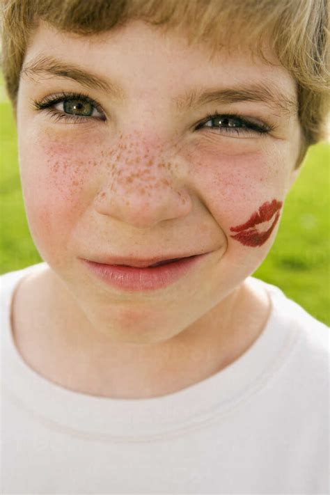 Grimacing boy with lipstick kiss on face stock photo