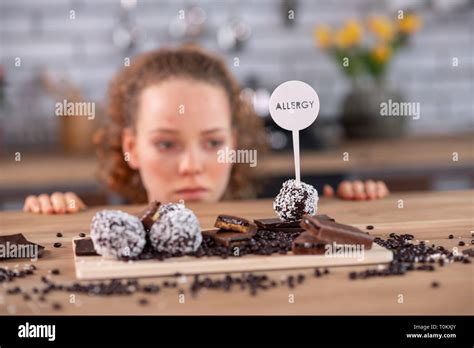 Tired curly-haired woman leaning on kitchen table while touching warning Stock Photo - Alamy