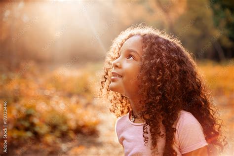 Afro american cute little girl with curly hair receives miracle sun rays from the sky Stock ...
