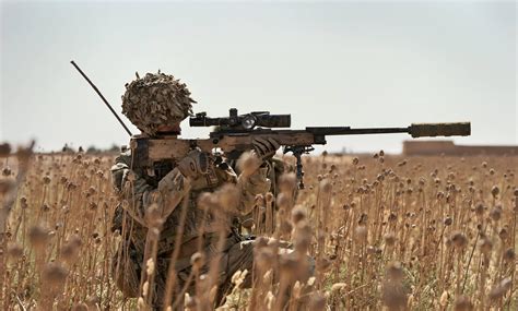 British Army sniper looks through the scope of his L115A3 Sniper Rifle during counter insurgency ...