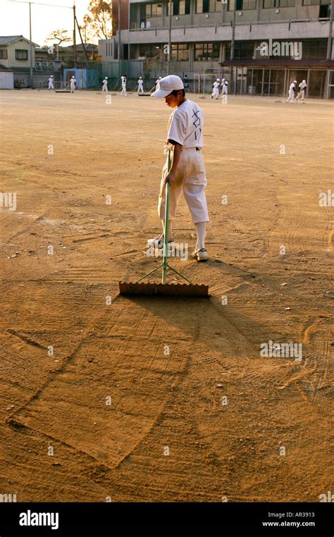 Japanese little league baseball players rake the ground after a game in ...