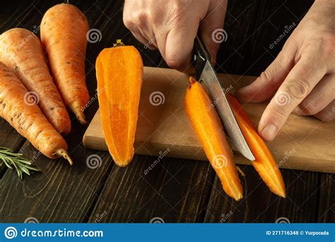 Cutting Raw Carrots on a Wooden Cutting Board with a Knife in the Hands ...