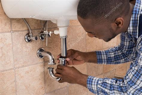 Plumber Hand Fixing Sink In Bathroom — Stock Photo © AndreyPopov #117548894