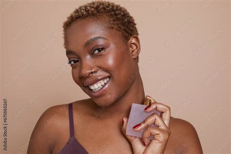 Studio portrait of smiling woman spraying perfume on neck Stock Photo ...