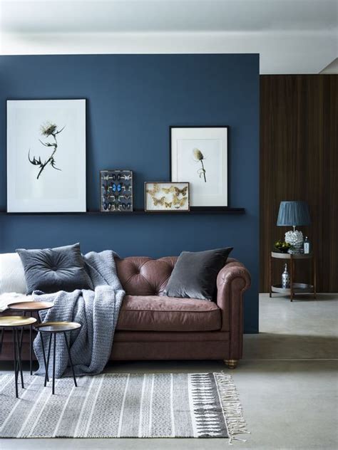 chic seating area with a brown sofa and a navy accent wall and textiles ...