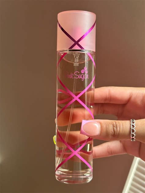 a person holding up a bottle with pink ribbon on the top and one hand ...